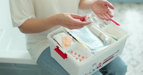 Woman Takes Pills From First Aid Kit
