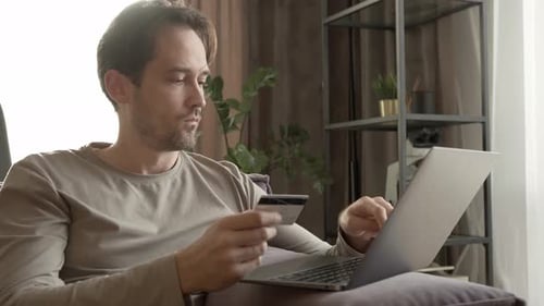 Man Using Credit Card and Laptop at Home