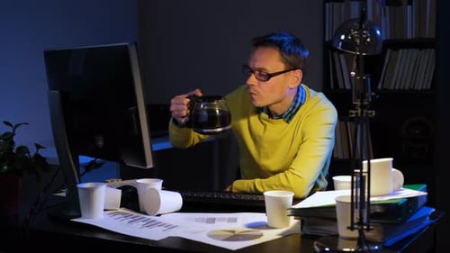 Adult Drinking Coffee at Desk in Overtime