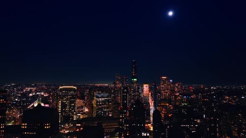 The Moon in the dark blue sky over the scenery of New York. Vast city view at night