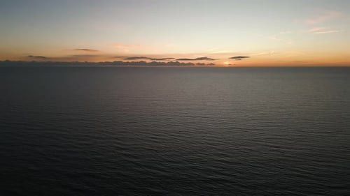 Orange sunset sky and endless seascape horizon, aerial view