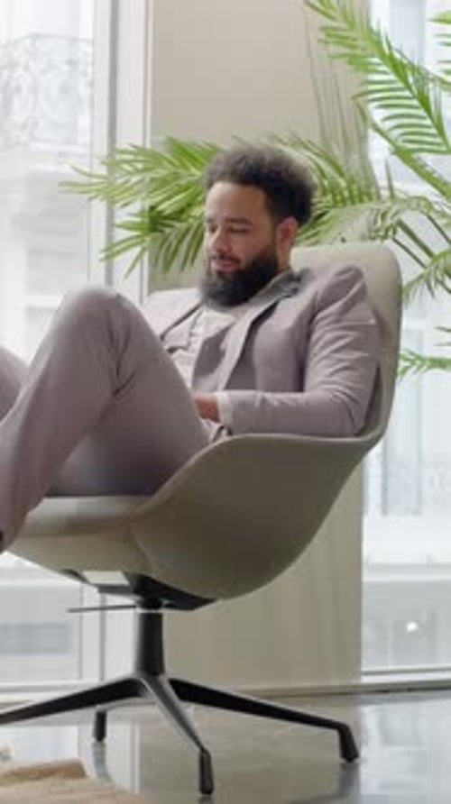A Professional African American Man is in a Sleek Modern Office Focused on His Work