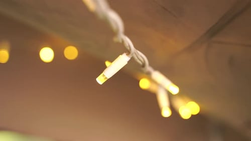 A close-up shot of hanging fairy lights. The lights are bright and yellow. The lights create a warm