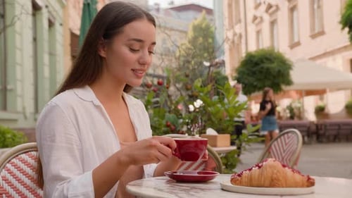 Smiling European Girl Woman Tourist Enjoying Breakfast Hot Coffee Croissant in City Cafe Terrace