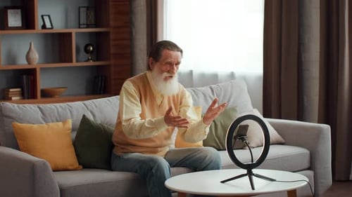 Senior Man Talking to Phone on Ring Light Stand