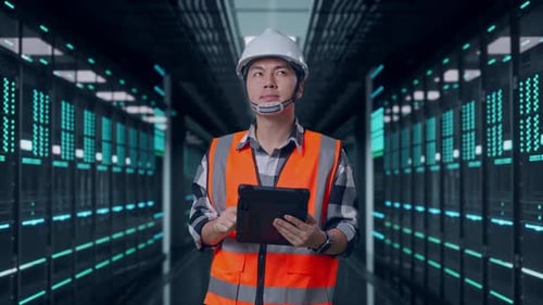 Asian Male Engineer Looking At The Tablet In His Hand in Data Center