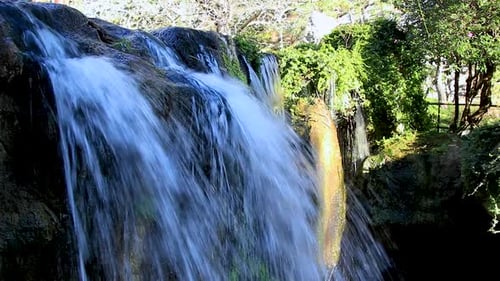 Small water in a Chinese garden flowing over a rock face rapidly.