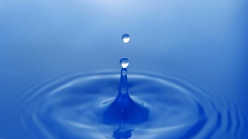 Water Drop Creates Ripples on a Blue Surface