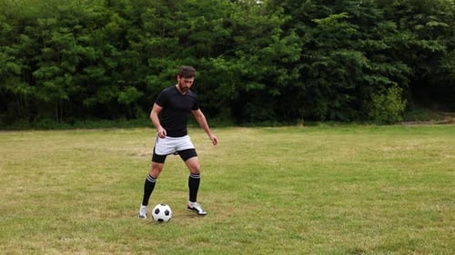 Male Soccer Player Juggling Ball on Grass Field