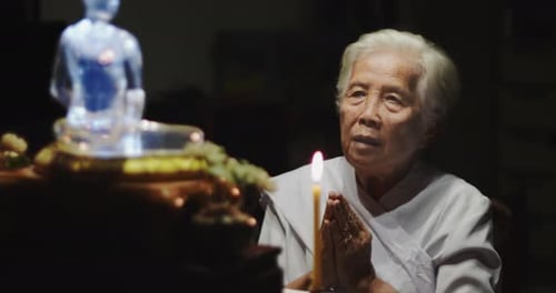 Senior Woman Praying with Candle at Night