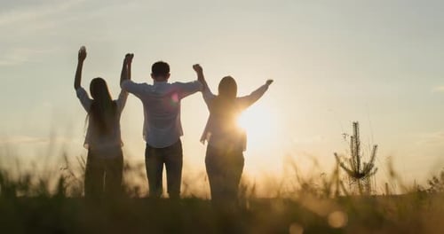 Silhouettes of a Group of Friends Holding Hands and Then Raising Them Up Success and Startup Concept
