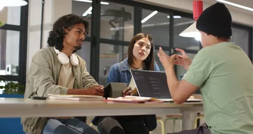Des pairs diversifiés collaborent en tant que locuteur droit faisant des gestes, expliquant le code de l'ordinateur portable avec l'appareil à la table