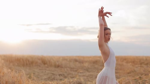 Elegant Woman in White Dress Moving on Field During Sunset