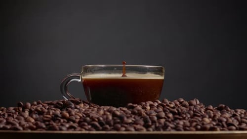 Gouttes de café parfumées tombant dans une tasse d'espresso pleine, gros plan. Mug transparent