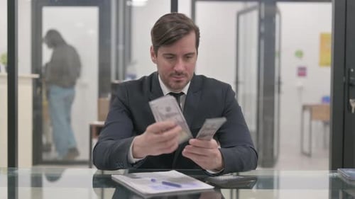 Man in Suit Counting Money at Desk
