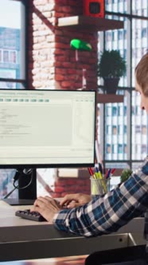 Man in Home Office Looking at Green Screen Tablet and Computer Typing Code
