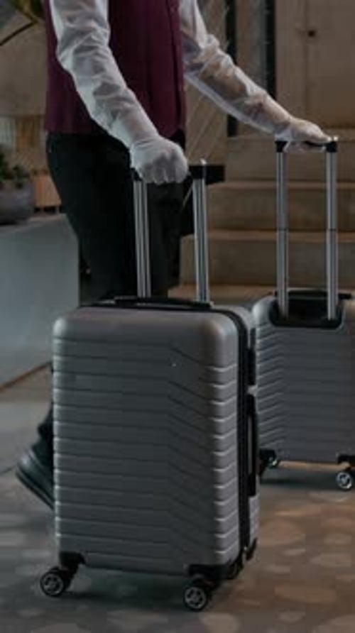 Bellhop Rolling Guest Luggage through Hotel Lobby Area