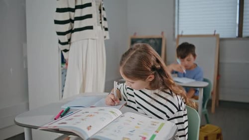 Smart Girl Writing Exercises in Notebook in Elementary School Class Closeup
