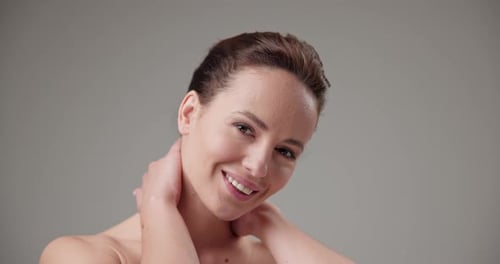 Smiling Woman Touches Neck and Shoulders