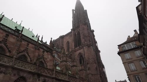 View onto the Strasbourg Cathedral against a cloudy sky backdrop, the tower rises proudly, flanking