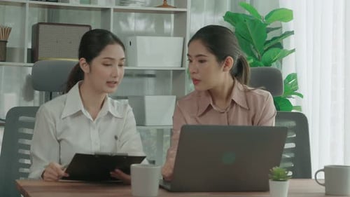 Two Young Enthusiastic Businesswoman Working Together in the Office Workspace