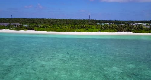 Maldives coast in sunny weather with bright colours. Turquoise waters, white beach and green lush fo
