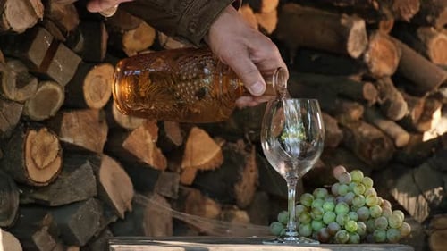Sommelier pouring white dessert wine in glass. Filling wine glass outdoor