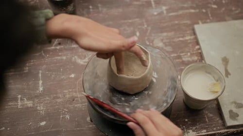 Person Modeling Clay at Table in Pottery Workshop