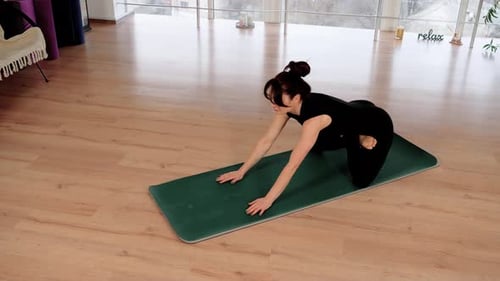 Young Woman Wearing Sportswear Practicing Yoga in Light Studio with Big Windows Flexible Female