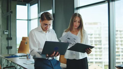 Colleagues Discussing Project Details in a Modern Office Setting During a Sunny Afternoon
