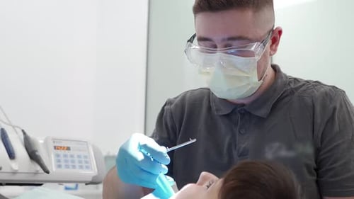 Male Dentist Cleaning Root Canal and Cauterizing Dental Nerve in the Modern Dental Clinic Oral