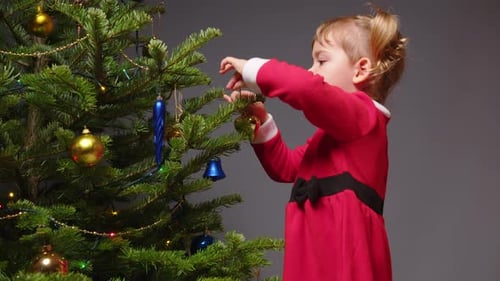 Little Girl Decorating Christmas Tree With Colorful Ornaments