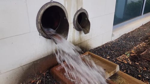 Water Flowing From Pipes Onto Wood and Rocks