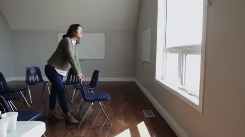 Mature woman leaning in community center looking through window with hope