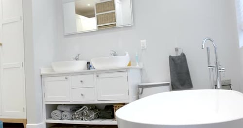 General view of bathroom with bathtub at home, mirror and washbasin, slow motion