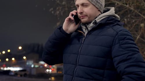 Man receives a serious phone call standing outdoors in the city, handheld view with copy space