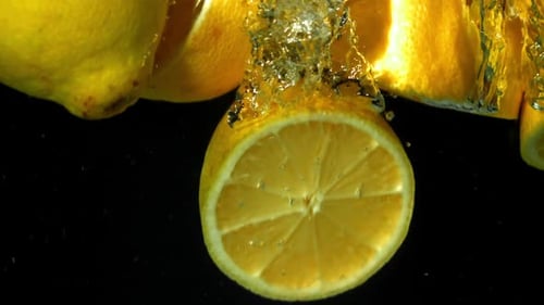 Fresh Sliced Lemons Dropping into Water on Black