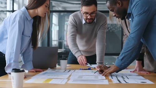 Brainstorming, standing by the table. Professional workers are in the modern office together.