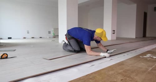 Man Installing Laminate Flooring in Bright Room
