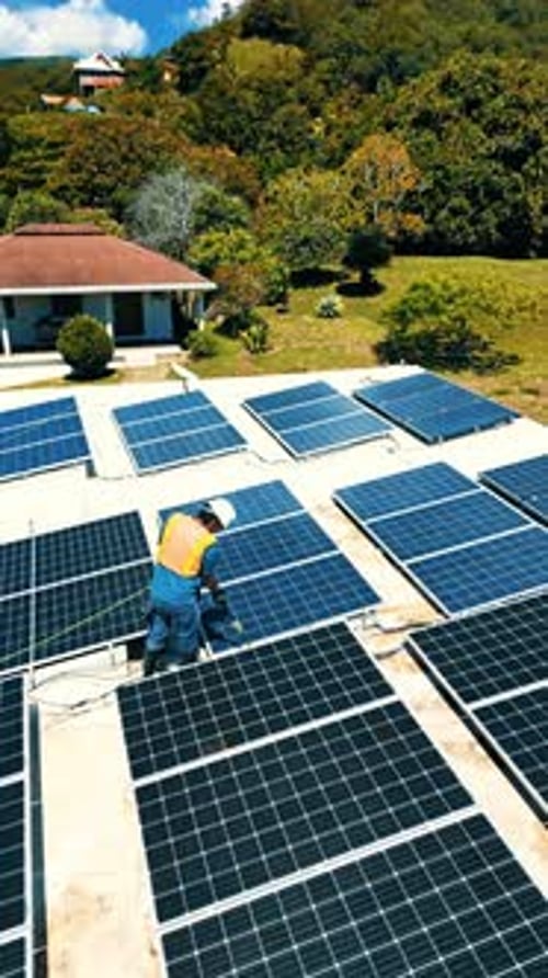 Vue aérienne d'un ouvrier nettoyant des panneaux solaires au Honduras.