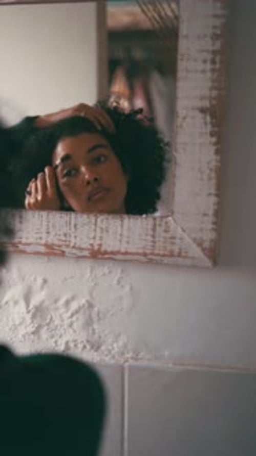 Woman Applying Eye Makeup in Bathroom Mirror