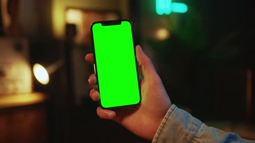 In the Evening Hands Man Holding and Using Mobile Phone with a Vertical Green Screen Indoors Social