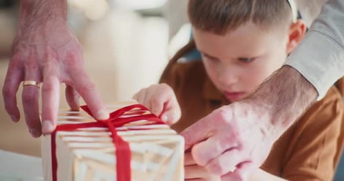 Child Receives Help Opening Wrapped Birthday Gift