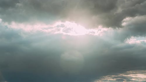 Les rayons du soleil brillent à travers les nuages sombres dans un ciel bleu nuageux, fond naturel, Time Lapse, naturel
