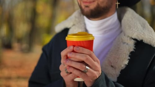 Man Sipping Hot Drink Outdoors in Fall