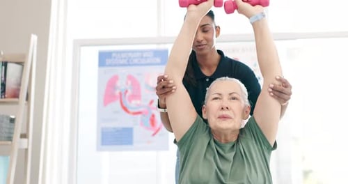 Senior Woman Assisted with Arm Exercises Using Dumbbells
