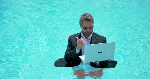 Geschäftsmann im Anzug arbeitet im Schwimmbad am Laptop, Reisen, Tourismus und Geschäftskonzept verrückt