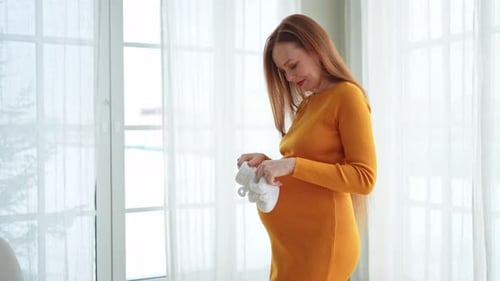 Pregnant Woman with Baby Shoes at Home