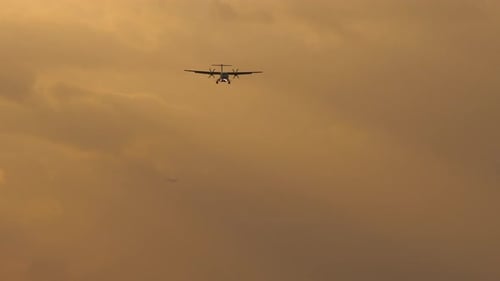 Twin Engine Aircraft Flying at Tropical Sunset
