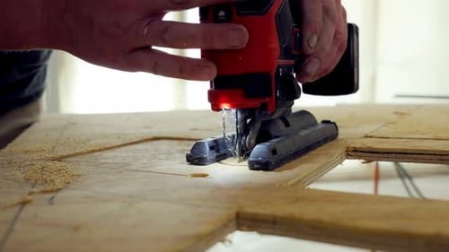 Person Using the Jigsaw Power Tool Worker is Holding Jigsaw with the Both Hands Guiding It Along
